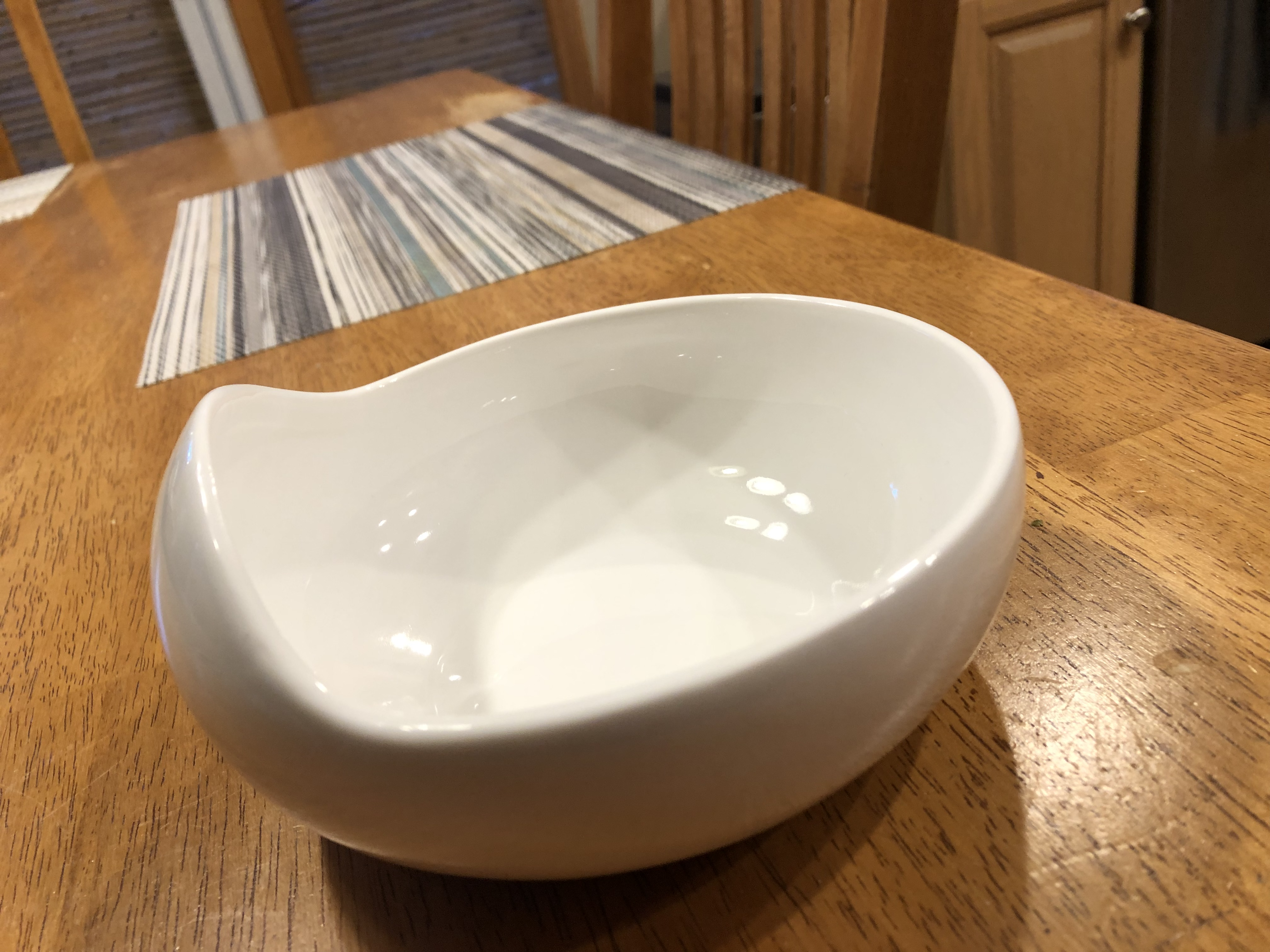 The Palada bowl on wooden table showing its elegant curved design and glossy finish