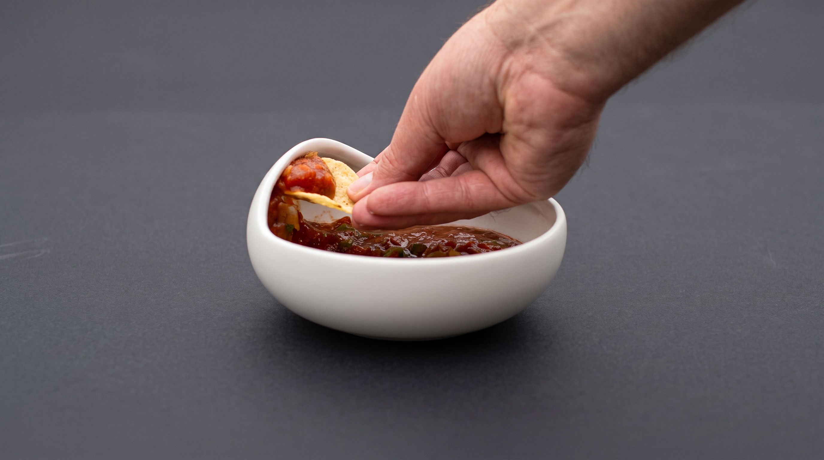 A hand lifting a loaded chip from The Palada's raised edge